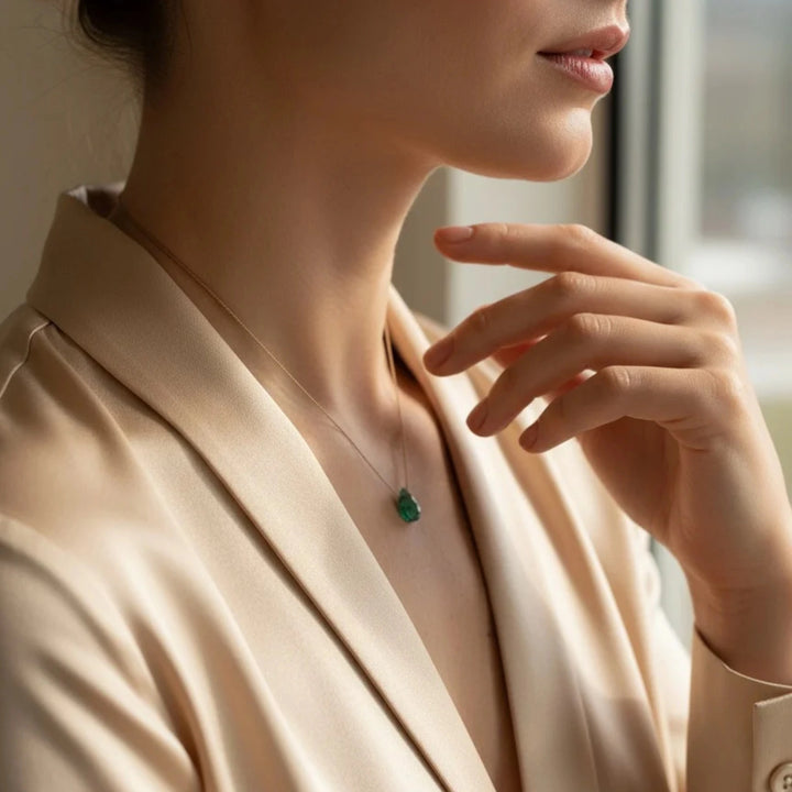 Woman wearing a necklace with an emerald pendant indoors