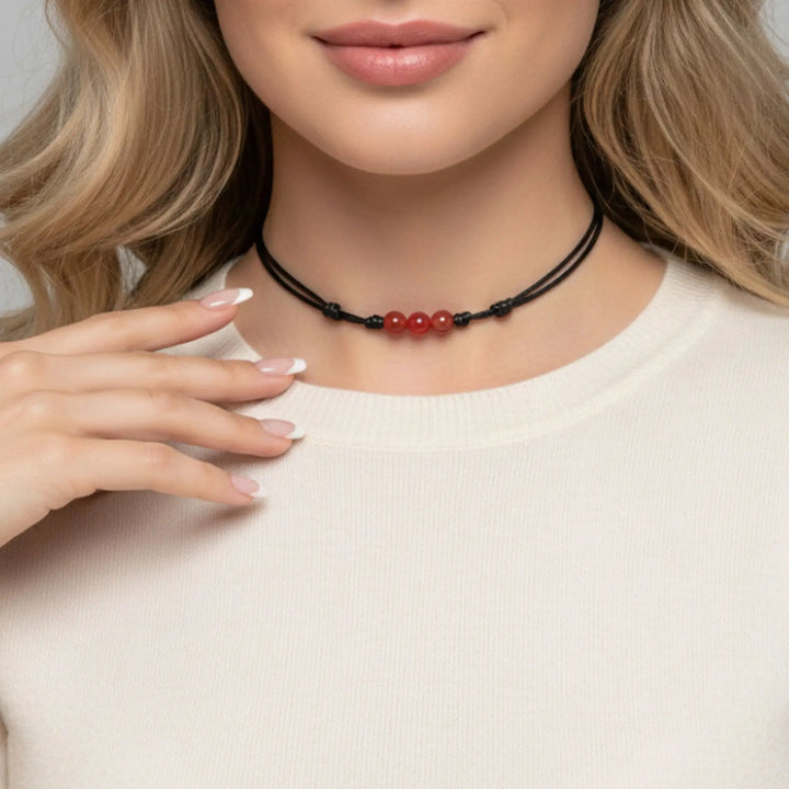 Necklace with red beads worn by a person against a neutral background