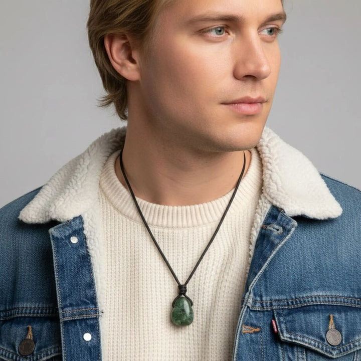 Man wearing a denim jacket with a white sweater and a necklace with a green diopside pendant.