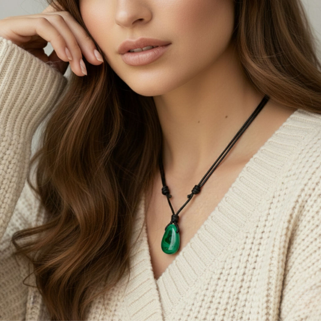 Woman wearing a necklace with a green malachite pendant, close-up of her neck and chest.