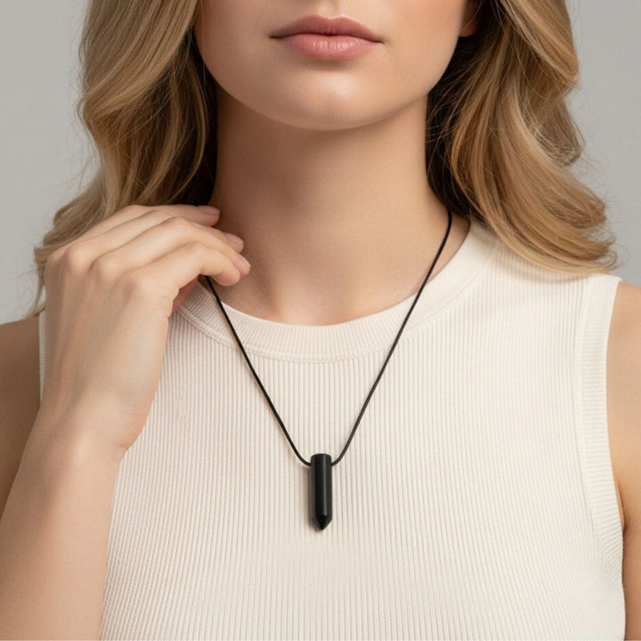 Woman wearing a black pendant necklace against a neutral background