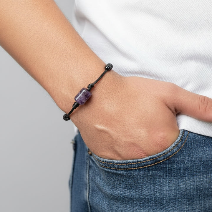 Hand wearing a bracelet with a purple amethyst  bead on a black background