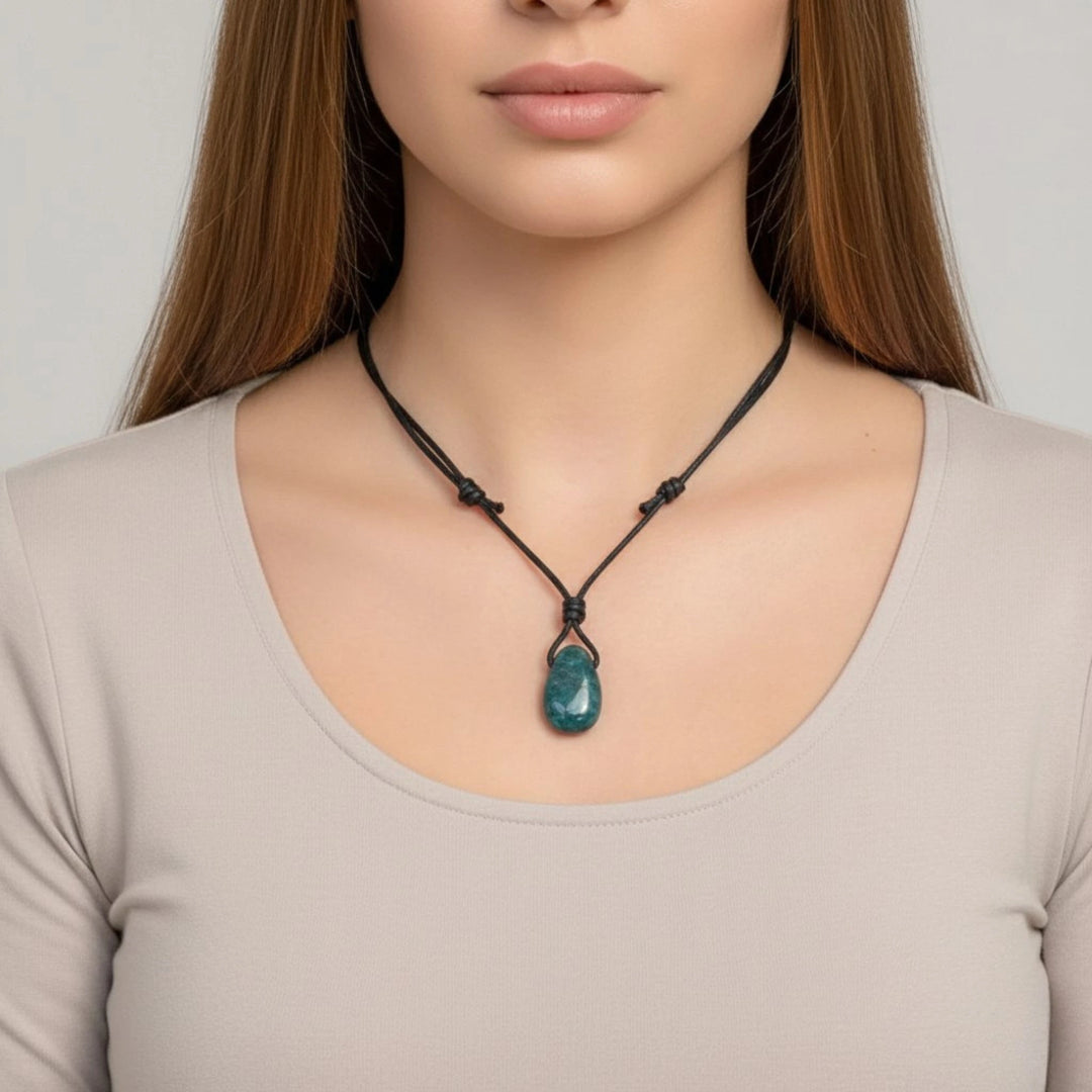 Woman wearing a necklace with a green Apatite pendant against a neutral background
