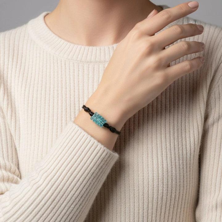 Person wearing a glass bracelet with aqua beads on a neutral background