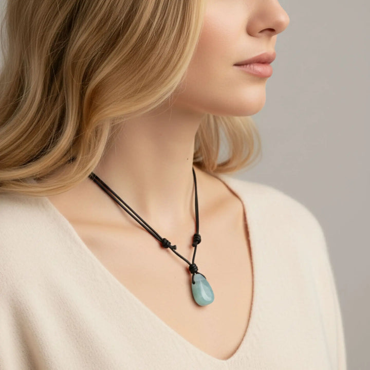 Woman wearing a necklace with a pendant against a neutral background