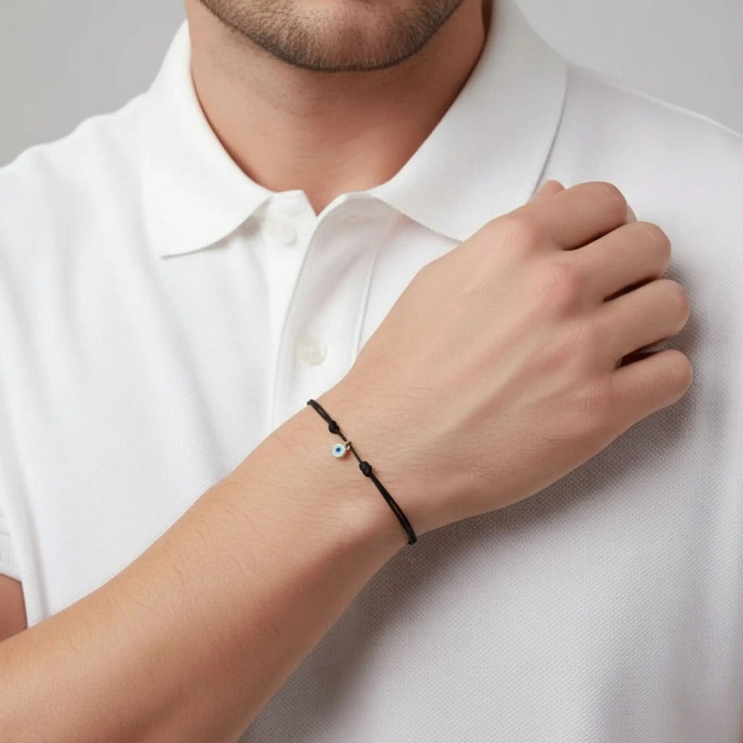 Man wearing a white polo shirt with a black string evil eye and blurred background