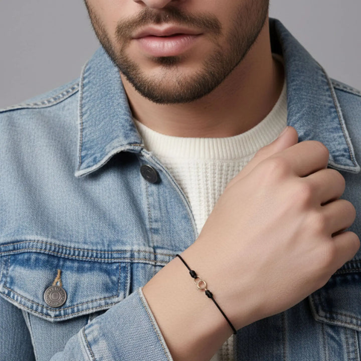 Man wearing a denim jacket and a bracelet on a gray background