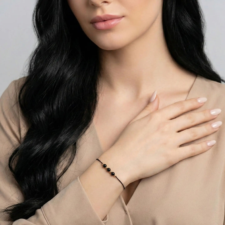 Woman wearing a black tourmaline beaded bracelet on her wrist with a neutral background