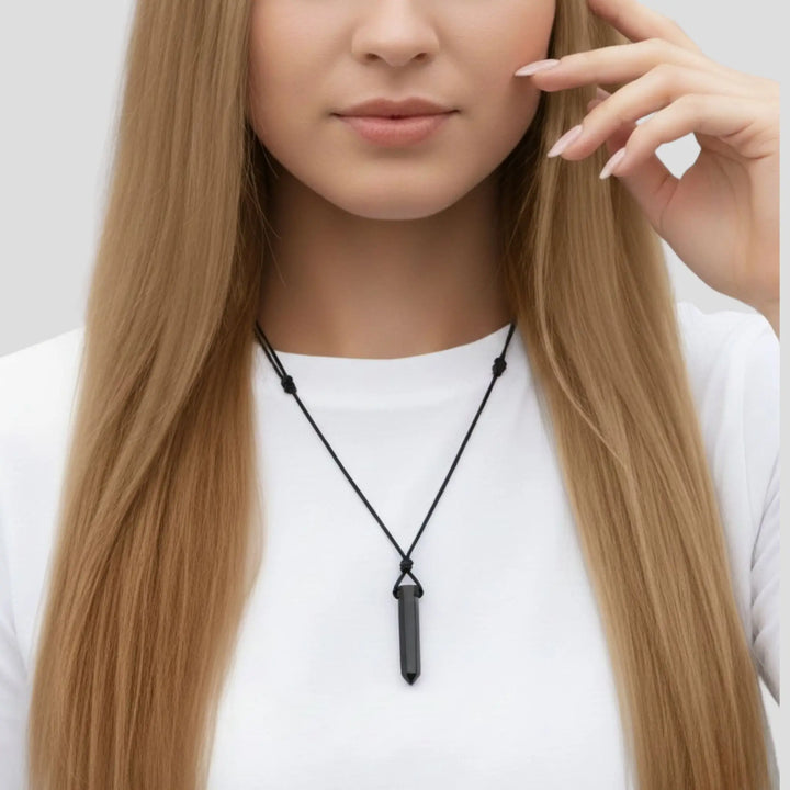 Woman wearing a black tourmaline  point necklace with a pendant on a white background