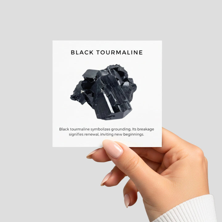 Hand holding a black tourmaline crystal with descriptive text on a light gray background