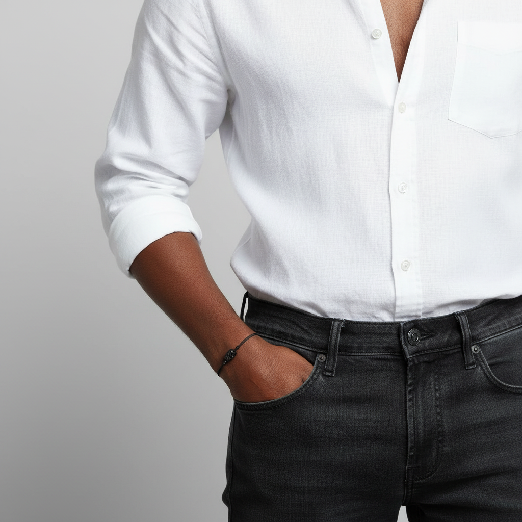 Person wearing a white shirt and black jeans with black tourmaline bracelet against a plain background