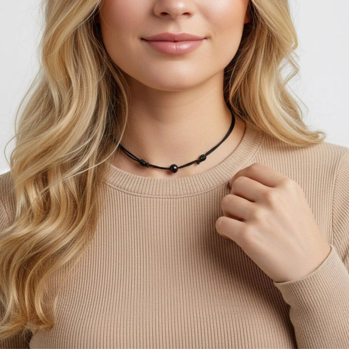 Woman wearing a black tourmaline beaded necklace with a plain background
