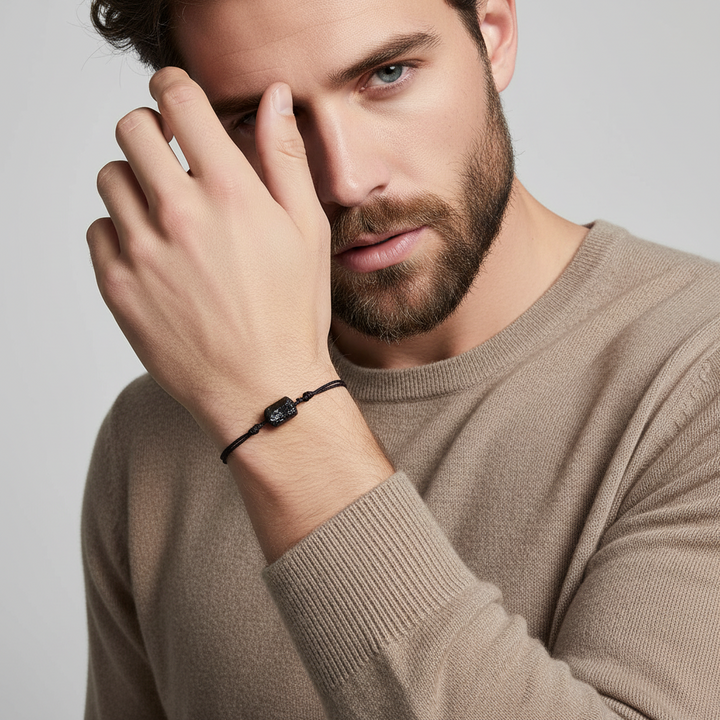 Man wearing a tourmaline bracelet on his wrist with a neutral background