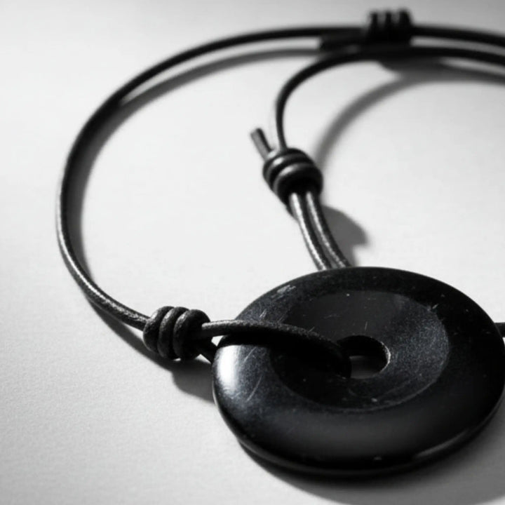 Black leather bracelet with a round black tourmaline stone on a light gray background