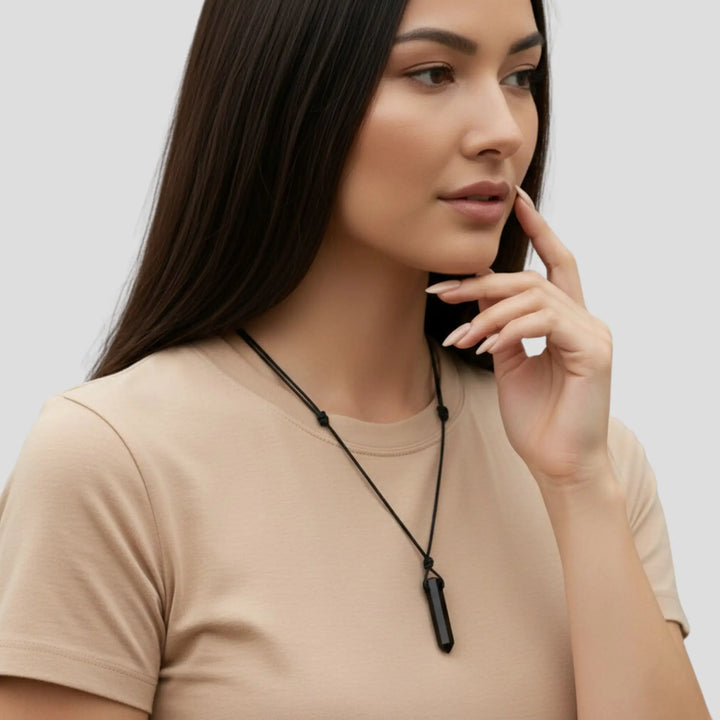 Woman wearing a black tourmaline  necklace against a plain background