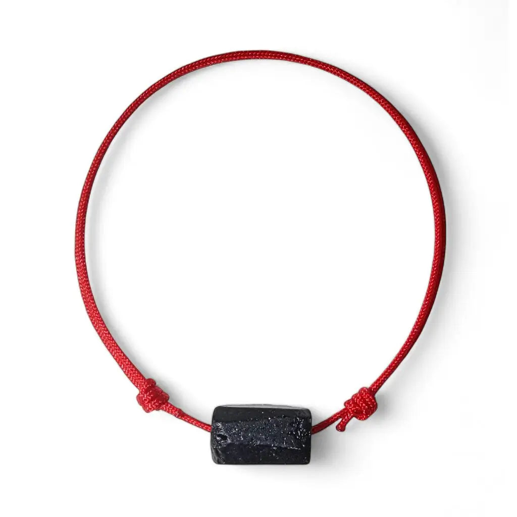 Adjustable red bracelet with a black tourmaline centerpiece and red string.