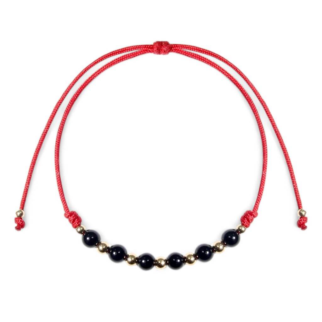 An adjustable red bracelet featuring black tourmaline beads and 14K gold accents.