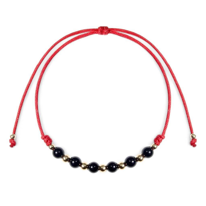 An adjustable red bracelet featuring black tourmaline beads and 14K gold accents.