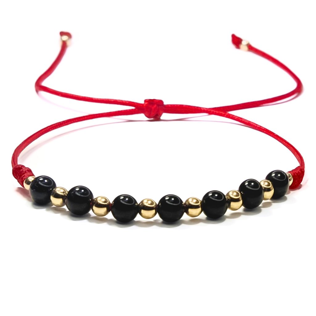 An adjustable red bracelet featuring black tourmaline beads and 14K gold accents.