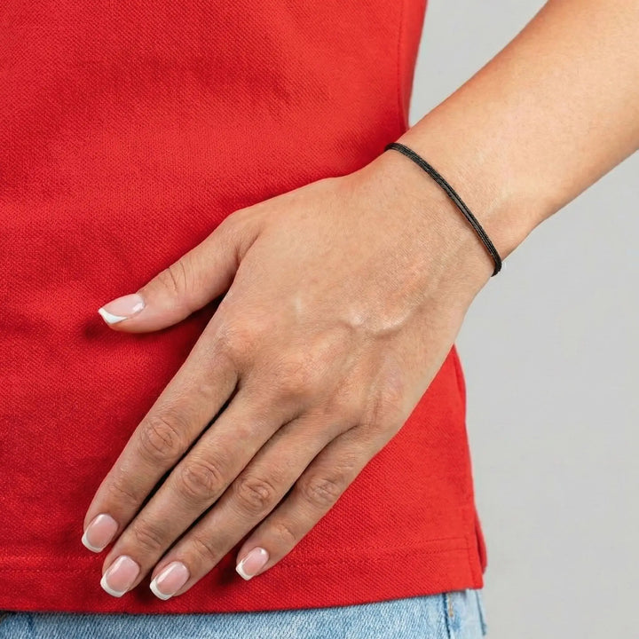 Hand with light nail polish on a red shirt against a gray background