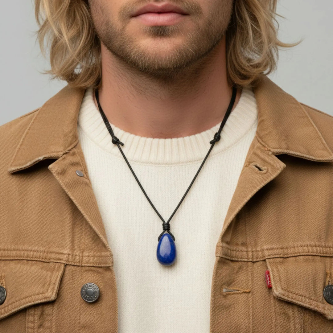 Man wearing a brown jacket and white sweater with a blue pendant lapis lazuli  necklace.