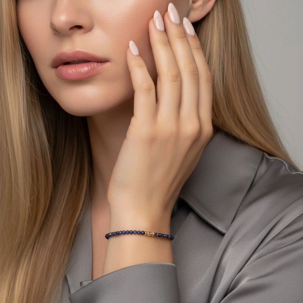Woman wearing a sapphire bracelet on her wrist with a neutral background
