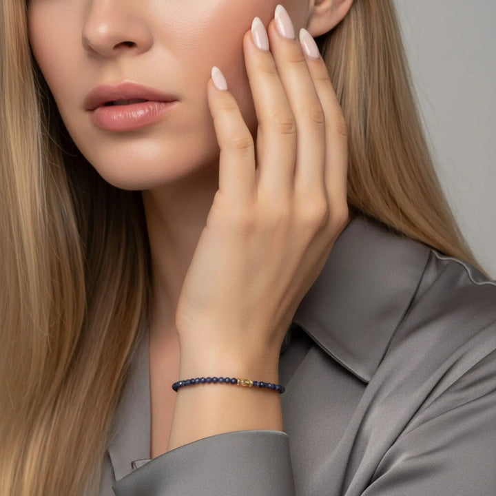 Woman wearing a sapphire bracelet on her wrist with a neutral background