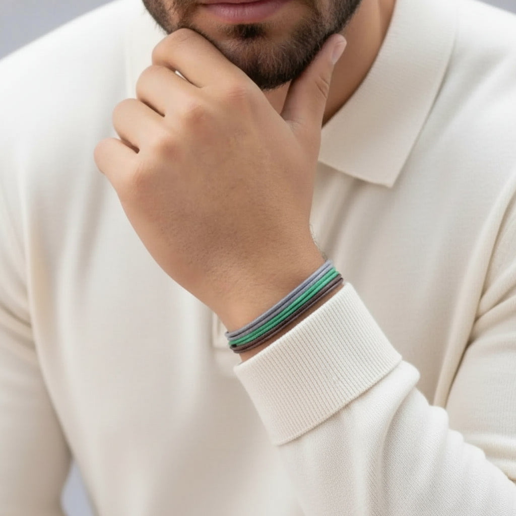 Person wearing a white sweater with a colorful bracelet on a neutral background