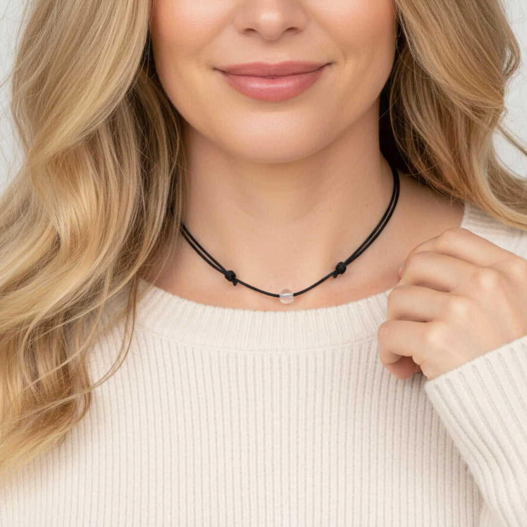 Woman wearing a clear quartz beaded necklace against a neutral background