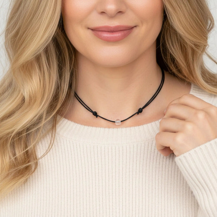 Woman wearing a clear quartz beaded necklace against a neutral background