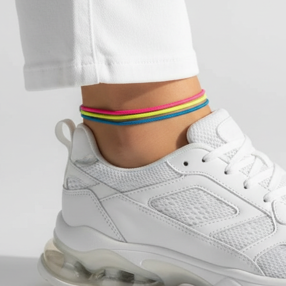 White sneaker worn with a colorful ankle stack on a light gray background
