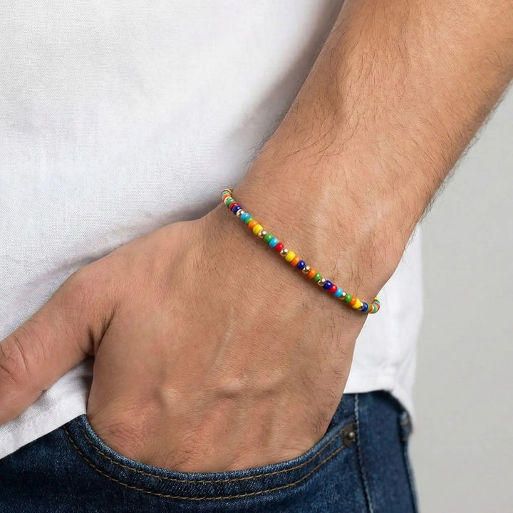 Multicolored beaded bracelet on a wrist with a plain background