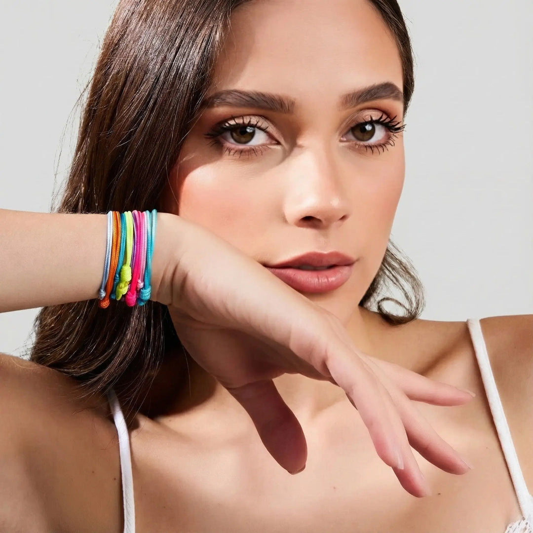 Woman wearing colorful bracelets on a plain background