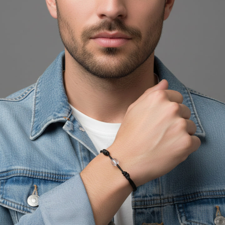Man wearing a black cord bracelet with crystal quartz beads on his wrist.

