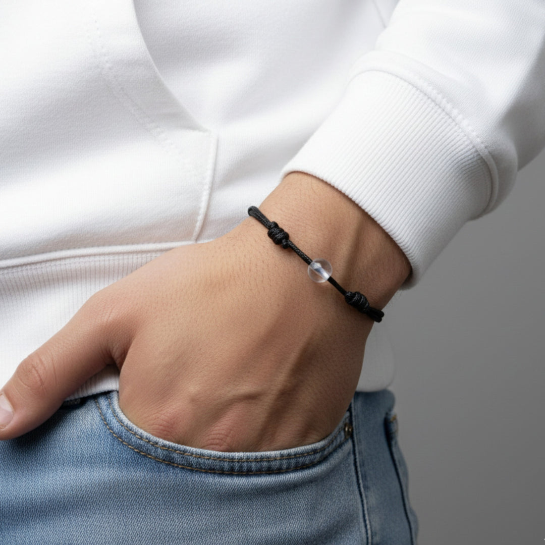 Man wearing a black cord bracelet with crystal quartz beads on his wrist.
