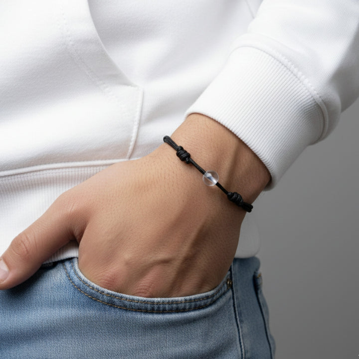 Man wearing a black cord bracelet with crystal quartz beads on his wrist.
