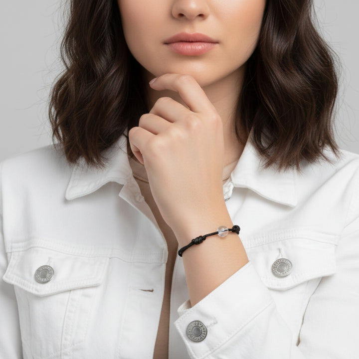 Woman wearing a black cord bracelet with crystal quartz beads on her wrist.

