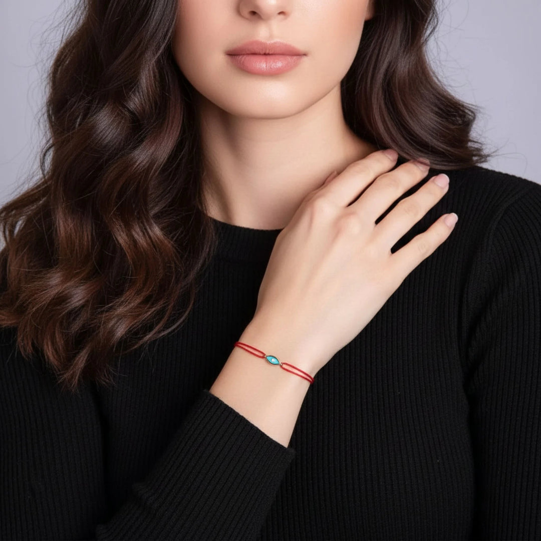 Woman wearing a red and turquoise bracelet on a plain background