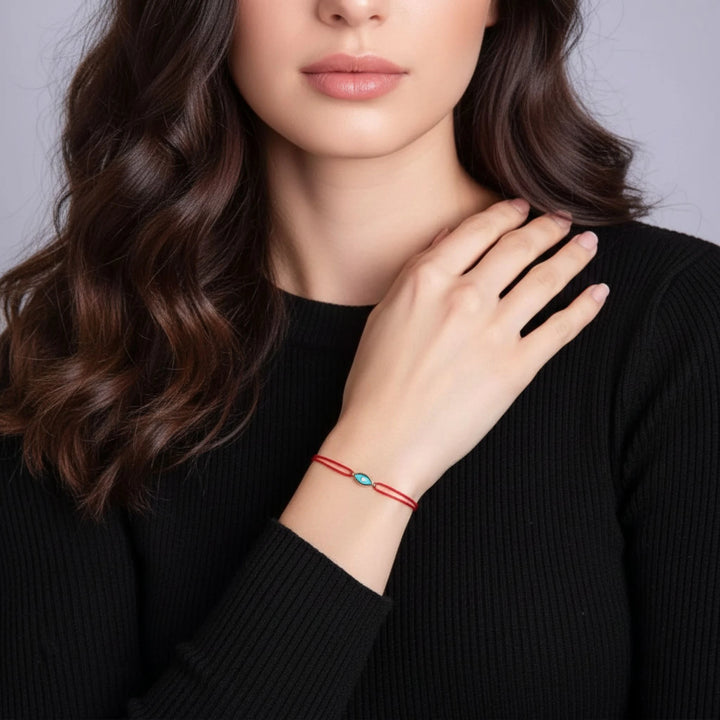 Woman wearing a red and turquoise bracelet on a plain background