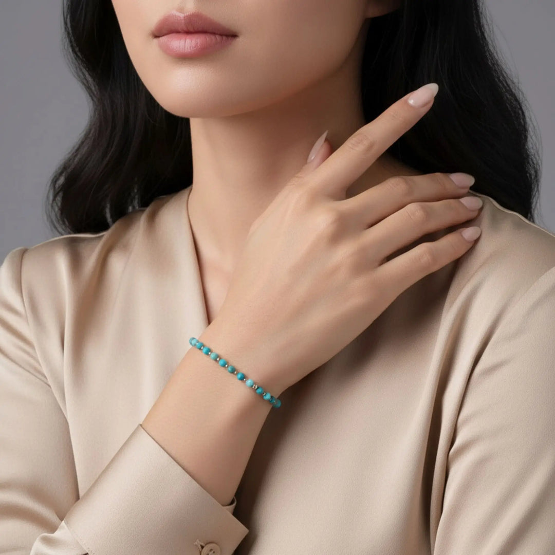 Woman wearing a turquoise beaded bracelet on a neutral background