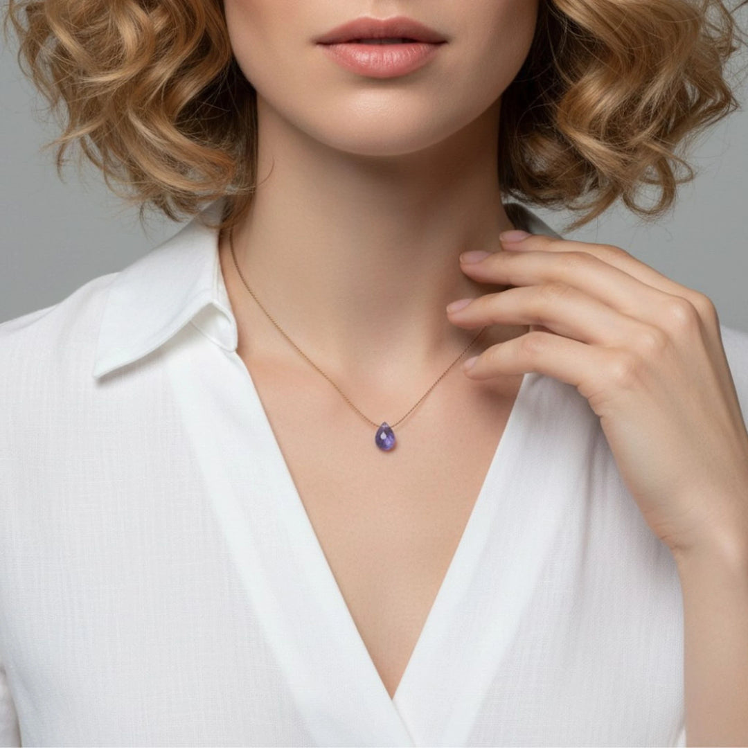 Woman wearing a necklace with a tanzanite gemstone against a neutral background