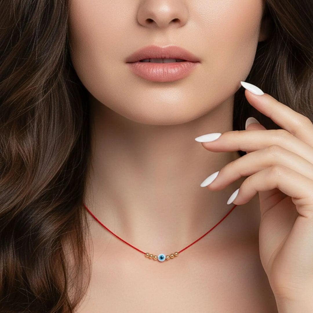 Close-up of a woman wearing a red evil eye necklace with a blue eye pendant.
