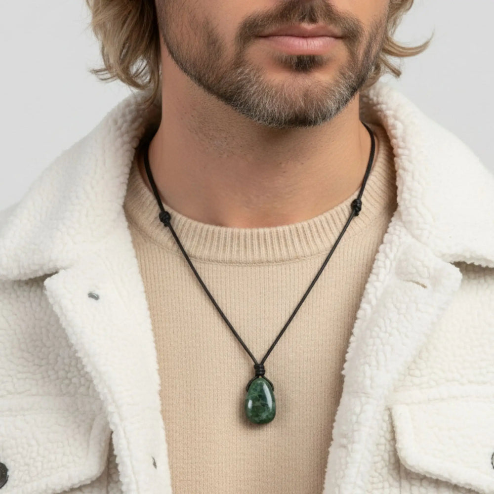 Man wearing a necklace with a green diopside pendant against a neutral background