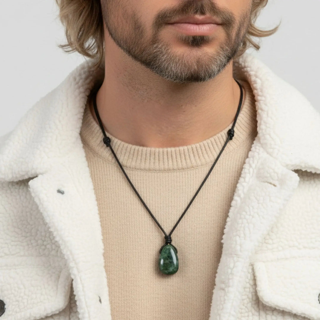 Man wearing a necklace with a green diopside pendant against a neutral background