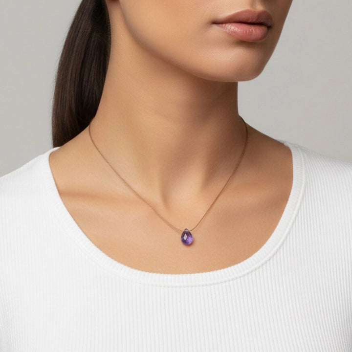 Woman wearing a necklace with a tanzanite pendant against a neutral background