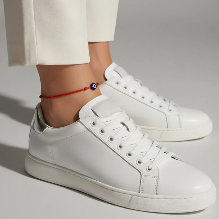 White sneakers worn with white pants on a gray background