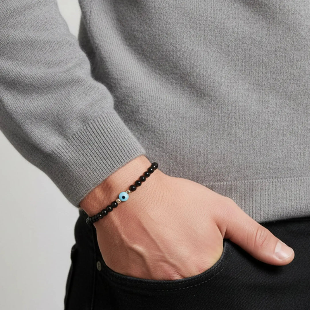 Person wearing a black tourmaline beaded bracelet with a blue bead on a neutral background