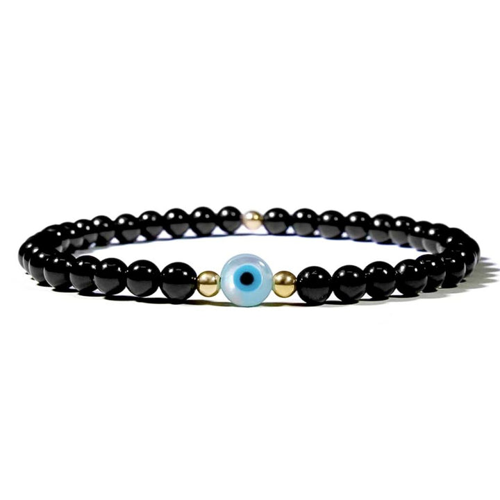 A black tourmaline and gold beaded bracelet with a mother of pearl evil eye charm.