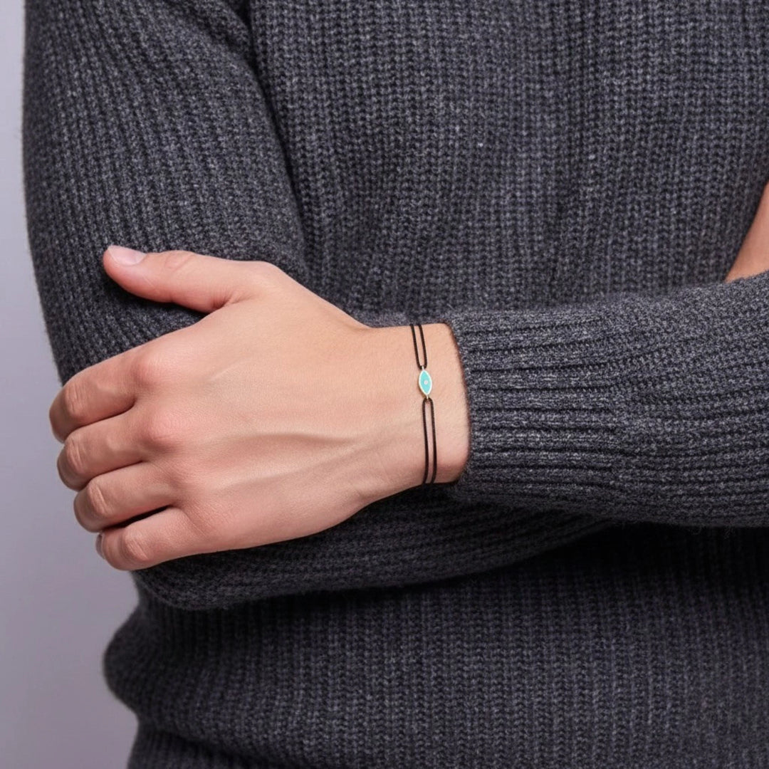 Person wearing a dark gray sweater with a bracelet on a plain background