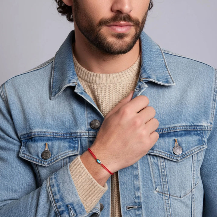 Man wearing a light blue denim jacket over a beige sweater with a neutral background